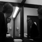 Photograph of girl looking into mirror with 4 reflections