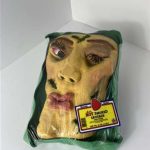 Clay face sculpture in meat carton