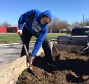 student digging in garden on service day